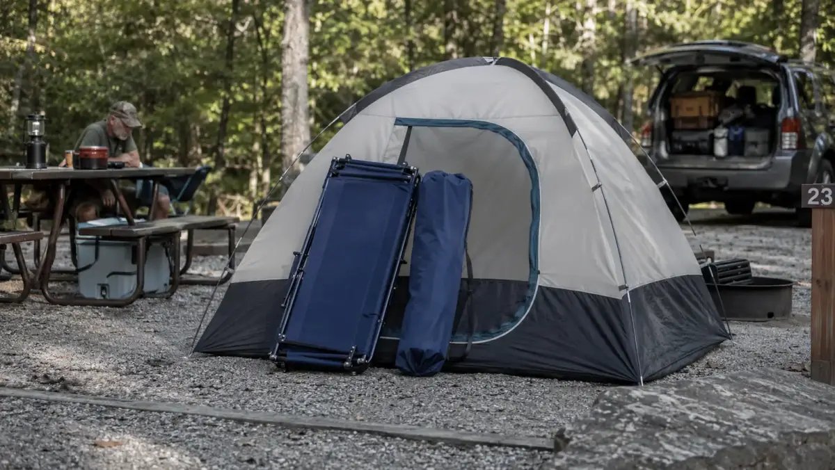 Folded ARAER camping cot and carry bag sitting next to a small dome tent that it would not fit inside