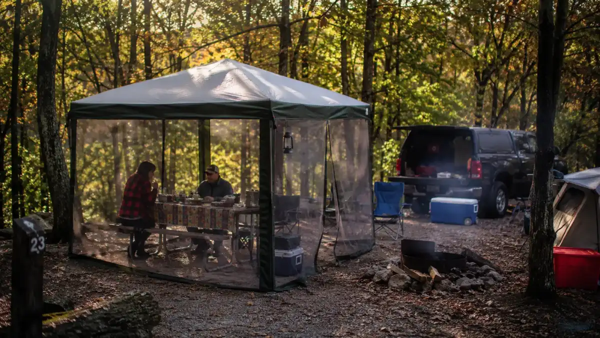 A weathered Alvantor pop up screen house set up at a campsite in autumn light, showing wear from repeated seasons of use